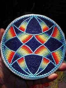 a hand holding a colorful beaded object in it's palm