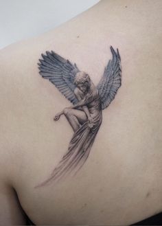 the back of a woman's shoulder with an angel tattoo on it