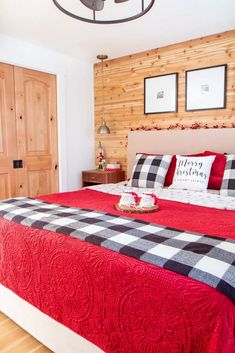 a bedroom with wood paneling and red bedding