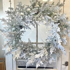 a white wreath with pine cones and snow flakes hanging from the side of a door