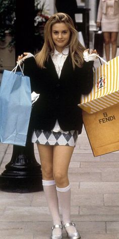 a young woman holding shopping bags while walking down the street