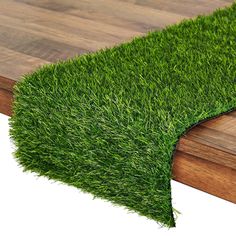 a wooden table topped with green grass on top of a hard wood planked floor