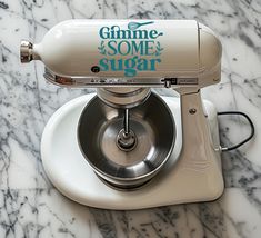 a white mixer sitting on top of a marble counter with the words gimme some sugar written on it