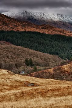 the mountains are covered in snow and brown grass