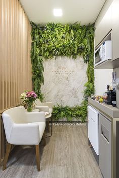 a kitchen with white chairs and green plants on the wall