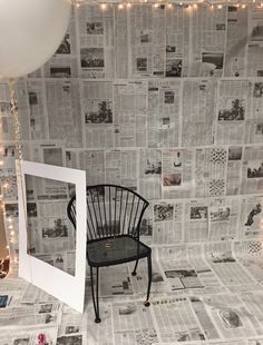 a chair sitting on top of a floor next to a wall covered in newspaper paper