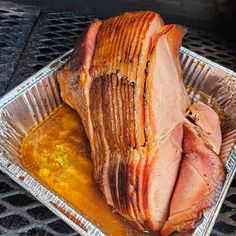 a large piece of meat sitting on top of a metal pan covered in sauces