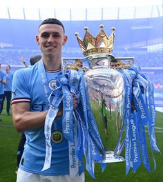 a man holding up a trophy on top of a soccer field in front of a crowd