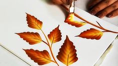 someone is painting leaves on a piece of paper