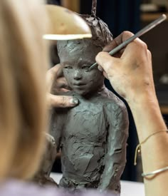 a woman is working on a clay statue