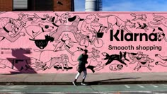 a person walking past a pink wall with cartoon drawings on it