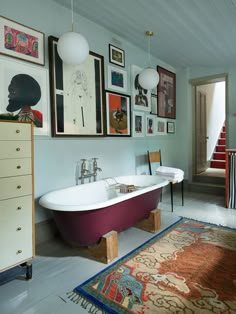 a bathroom with a bathtub, rug and pictures on the wall