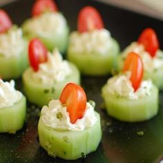 cucumber and tomato appetizers are arranged on a black plate, ready to be eaten