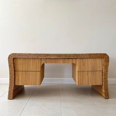 a desk made out of wicker sitting on top of a floor next to a wall