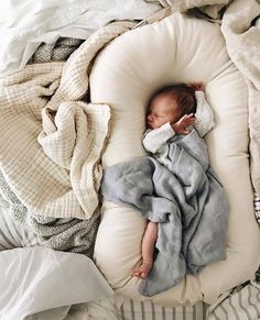 a baby wrapped in a blanket sleeping on a pillow