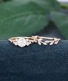 a close up view of a ring with leaves and diamonds on the front, sitting on a blue surface