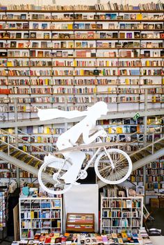 a bicycle is suspended in the air above bookshelves