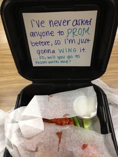 an open suitcase filled with food on top of a wooden table next to a sign that reads asking girl to prom ideas