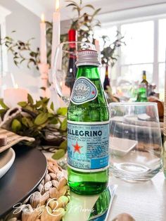 a bottle of beer sitting on top of a table next to wine glasses and plates