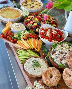 an assortment of food is displayed on a buffet table with flowers in the vases