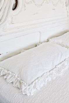 a white bed with ruffled edges and pillows