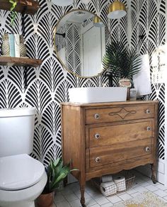 a white toilet sitting next to a wooden dresser under a mirror on top of a wall