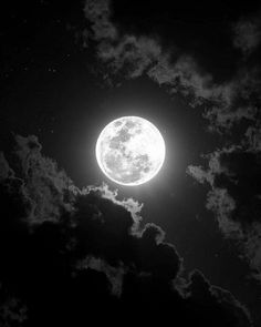 the full moon is shining brightly in the dark night sky with fluffy clouds and stars