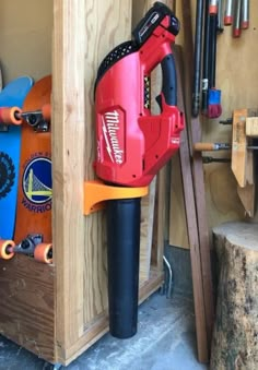 a red and black electric driller in a wooden storage area next to some tools