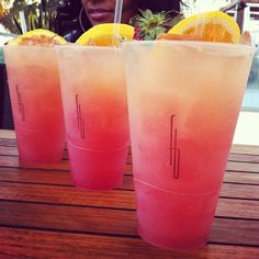 three pink drinks sitting on top of a wooden table