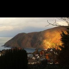 a view of a town and the ocean with mountains in the background