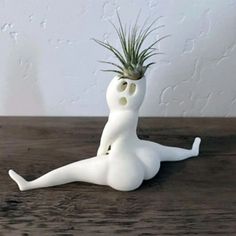 a small white planter sitting on top of a wooden table