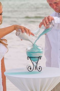 a bride and groom are pouring sand into a vase at their wedding on the beach