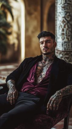 a man with tattoos sitting in a chair