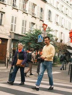 two people crossing the street in front of some buildings