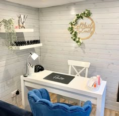 a white desk with blue chairs and shelves on the wall in a room that is decorated with wood planks