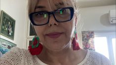 a woman wearing glasses with red and green tassels on her ears is looking at the camera