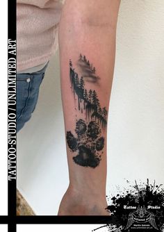 a person with a tattoo on their arm that has trees and mountains in the background