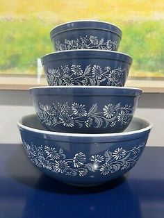 four blue bowls sitting on top of a counter next to a window with grass in the background