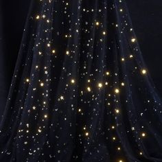 a black dress with gold stars on it and a sheer fabric over the skirt is shown