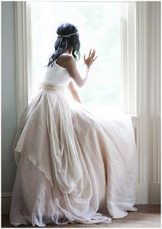 a woman in a white dress is looking out the window