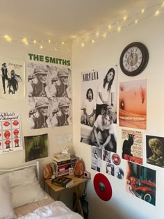 a bedroom with posters on the wall and a bed in front of it that has a small table next to it