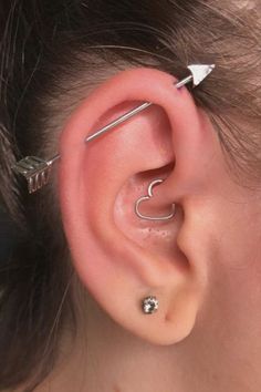 a woman wearing an ear piercing with two silver arrows