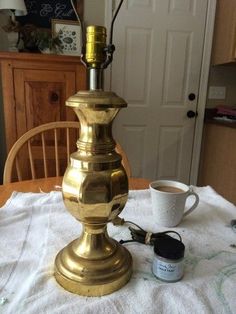 a gold lamp sitting on top of a table next to a cup