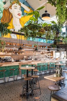 the interior of a restaurant with tables and stools in front of a mural on the wall