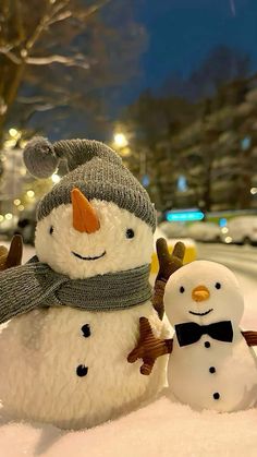 two snowmen standing in the snow wearing hats and scarves