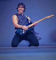 a man with an electric guitar in his hands and mouth wide open, posing for the camera