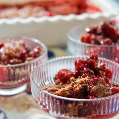 three glass bowls filled with cranberry toppings on top of a blue and white table cloth