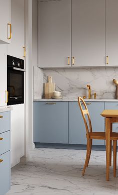 a kitchen with blue cabinets and white marble counter tops, gold pulls on the cupboards