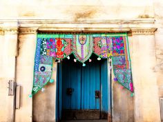 a blue door with an intricately designed curtain hanging over it's entrance to a building