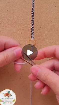 two hands are holding scissors and stringing together to make an origami necklace